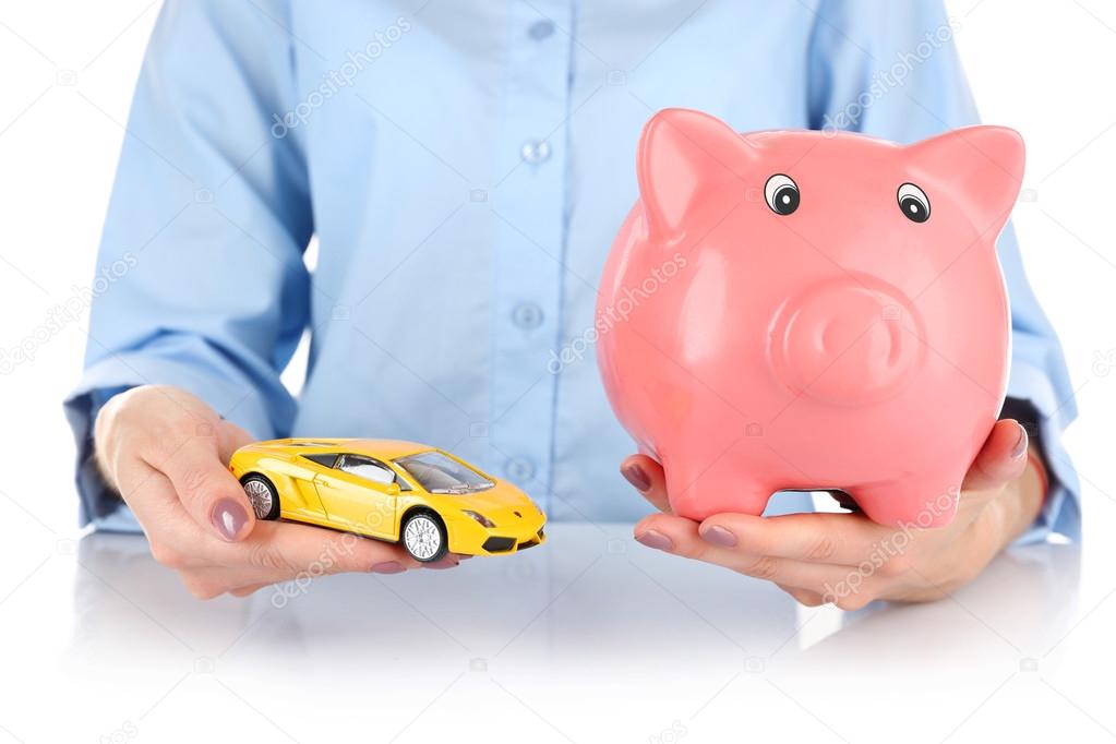 hands holding piggy bank and model of car