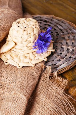 Tahta arka planda çiçek olan küçük hasır şapka.