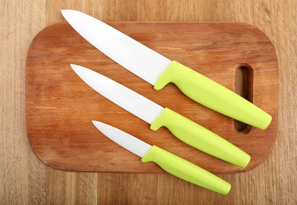 Cuchillos de cocina y tabla de cortar sobre mesa de madera —  Fotos de Stock