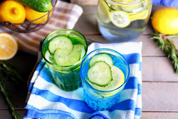 Agua dulce con limón y pepino en cristalería con servilleta sobre mesa de madera, primer plano —  Fotos de Stock