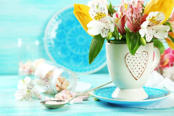 Beautiful flowers in cup, on color wooden background — Stock Photo, Image