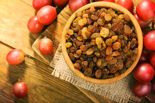 Raisins in bowl with grapes on table close up — Stock Photo, Image