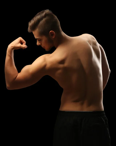 Muscle young man on dark background — Stock Photo, Image