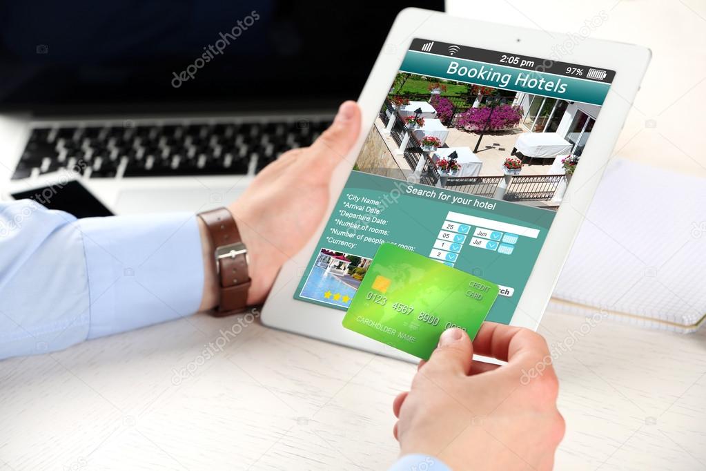 Man holding tablet with screen interface of booking hotels