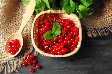 Olgun kırmızı kuş üzümü ahşap arka plan üzerinde hasır sepet