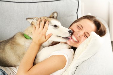 Malamute köpeğini odasında kanepede yatan kadın