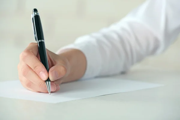 Mano femminile con penna scritta su carta sul posto di lavoro — Foto Stock