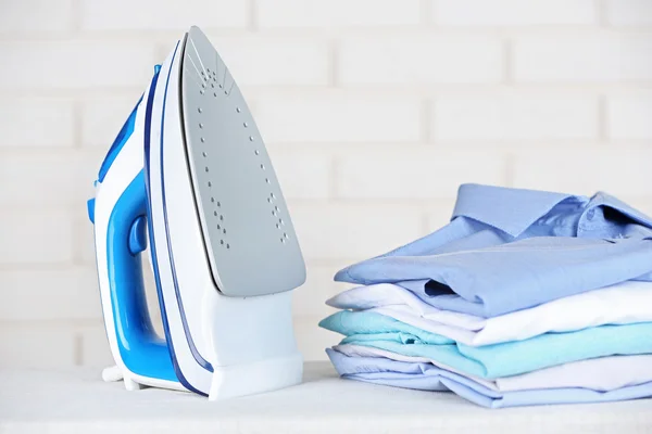 Electronic ironing and pile of clothes — Stock Photo, Image