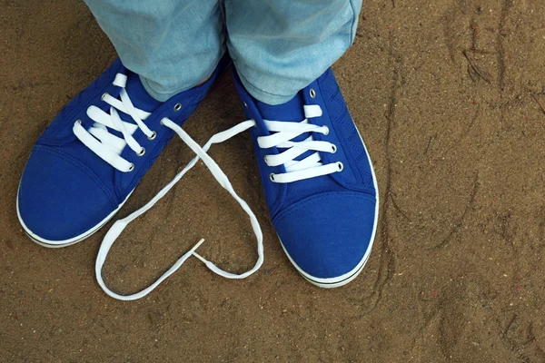 Female feet in gum shoes on sand background