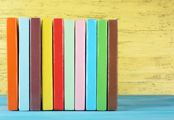 Kleurrijke boeken over gele houten achtergrond — Stockfoto