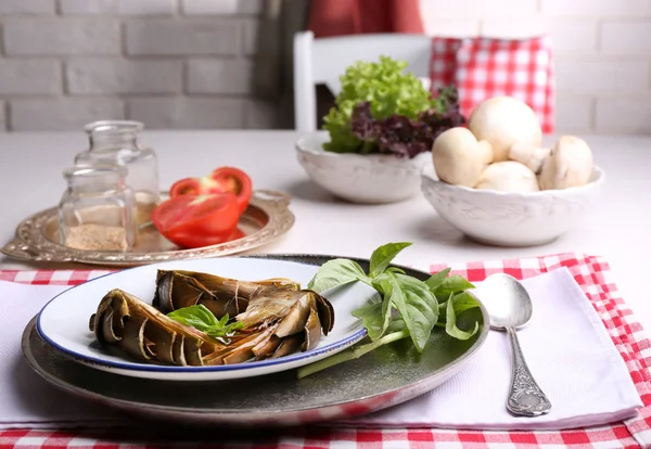 Carciofi arrosto su piatto, su fondo tavola cucina — Foto Stock