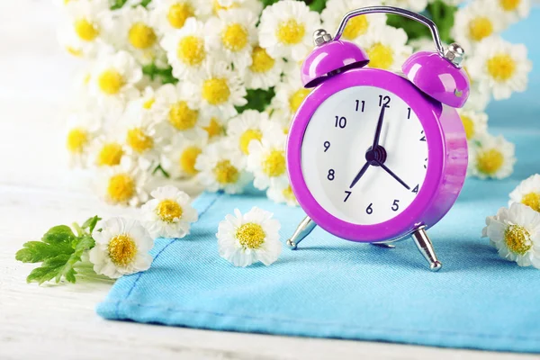 Pequeño despertador con hermosas flores —  Fotos de Stock