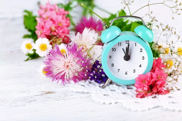 Pequeño despertador con hermosas flores —  Fotos de Stock