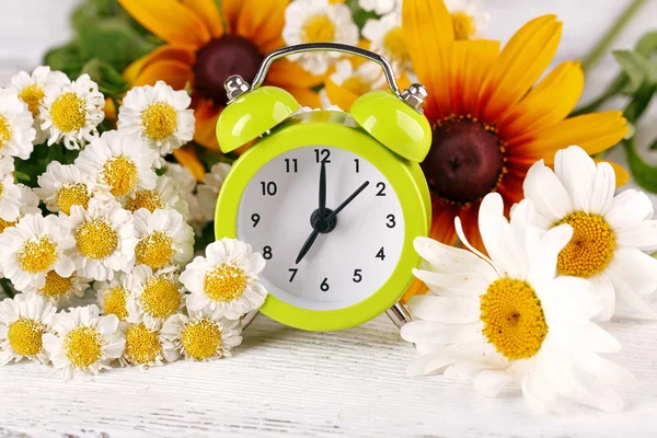 Pequeño despertador con hermosas flores — Foto de Stock