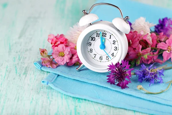 Pequeño despertador con hermosas flores —  Fotos de Stock