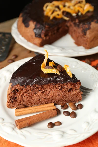 Torta con glassa al cioccolato e arancia su piatto, su fondo di legno — Foto Stock