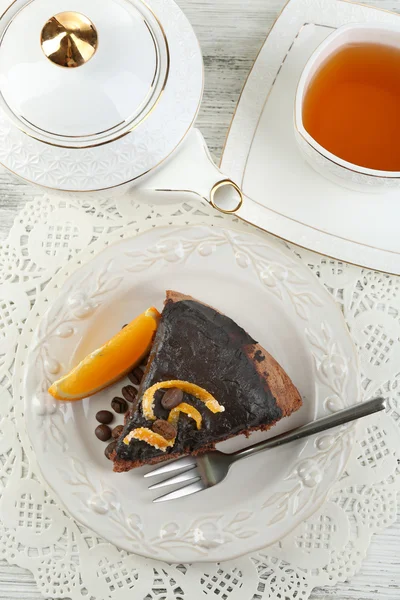 Tårta med choklad glasyr och orange på plattan, på trä bakgrund — Stockfoto