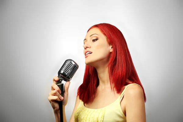 Mujer joven cantando con micrófono — Foto de Stock