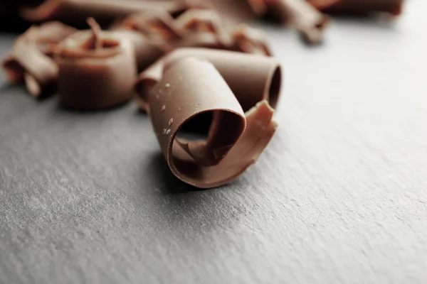 Čokoládové kudrlinky na dřevěný stůl zblízka — Stock fotografie