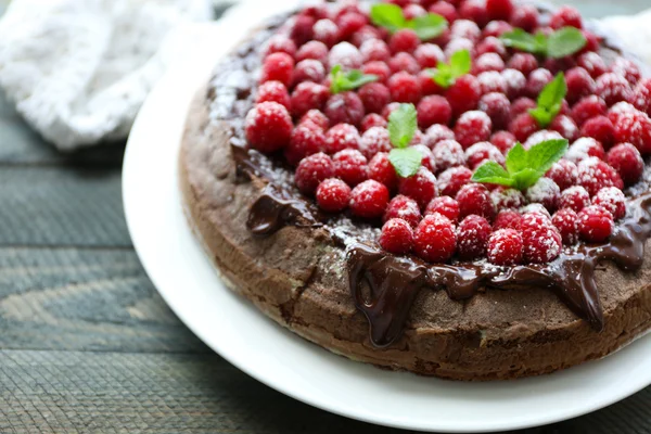 Kuchen mit Schokoglasur und Himbeeren auf Holzgrund — Stockfoto