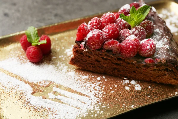 Kuchenstück mit Schokoglasur und Himbeeren auf Blech, Nahaufnahme — Stockfoto