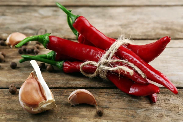 Rode hete pepers met kruiden op houten tafel close-up — Stockfoto