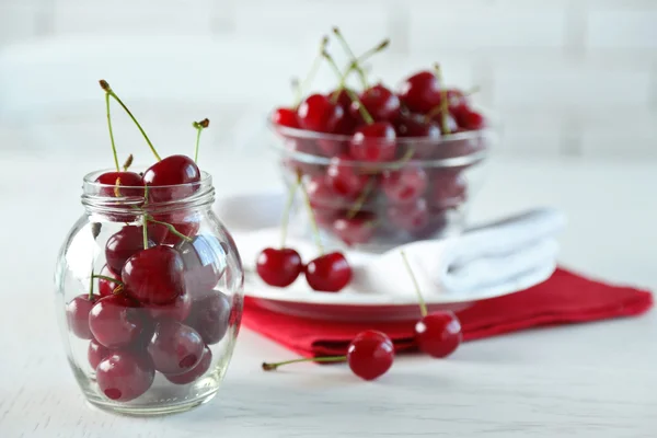 Cerezas en cuenco de vidrio en la mesa, sobre fondo claro — Foto de Stock