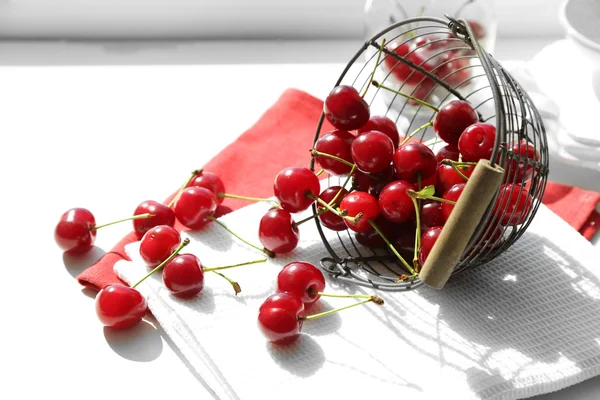 Cerezas en canasta sobre mesa, sobre fondo claro — Foto de Stock