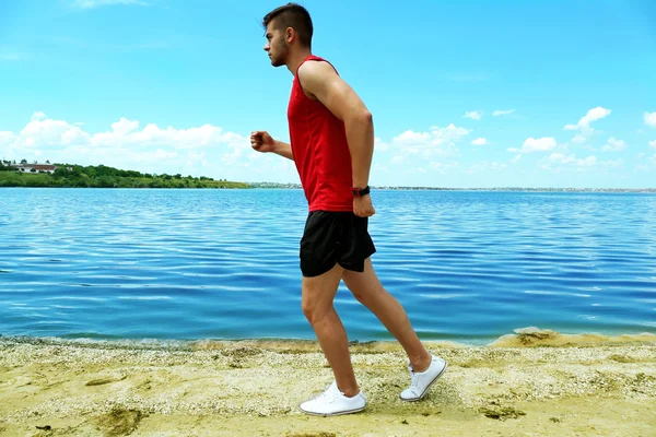 Ung man joggar på stranden — Stockfoto