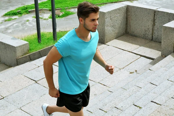 Young man jogging at stairs outdoors — Stock Photo, Image