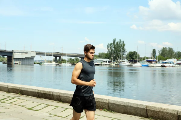 Young man jogging near river — Stock Photo, Image