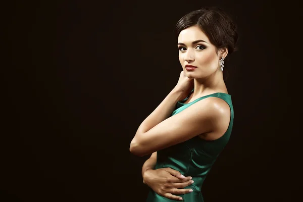 Atractiva mujer en vestido verde sobre fondo oscuro — Foto de Stock