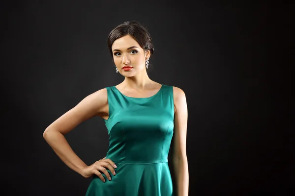 Atraktivní žena v zelených šatech na tmavém pozadí — Stock fotografie