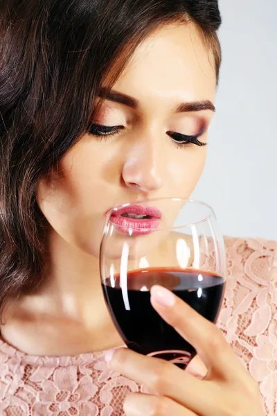 Porträt einer jungen Frau mit einem Glas Rotwein auf grauem Hintergrund — Stockfoto