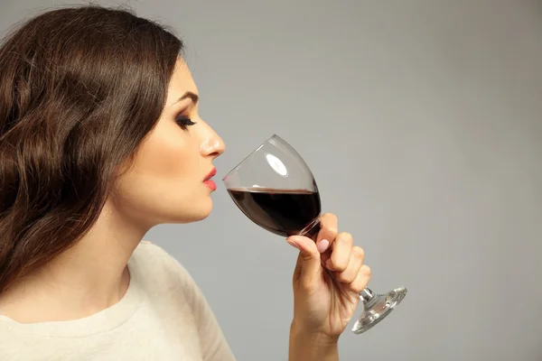 Retrato de jovem com copo de vinho tinto sobre fundo cinza — Fotografia de Stock