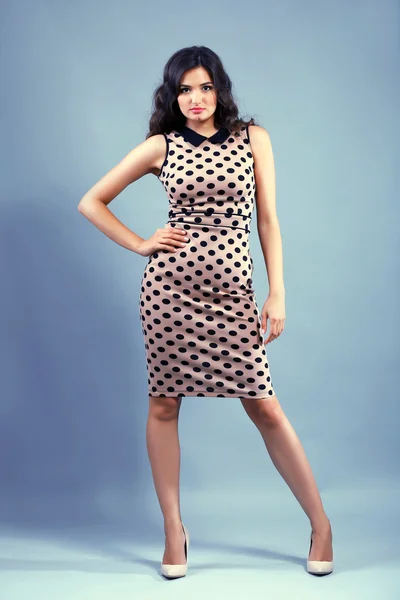 Portrait of young pretty woman in beige dots dress on grey background — Stock Photo, Image