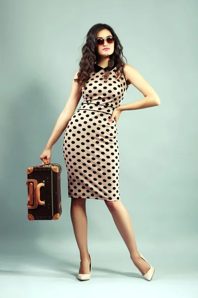 Photo de style rétro de jeune femme avec valise sur fond gris — Photo