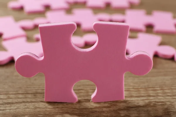 Pink puzzle pieces on wooden table — Stock Photo, Image