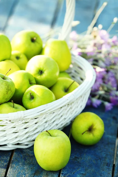 Green apples with bouquet of wildflowers on wooden table, closeup — Stock Photo, Image