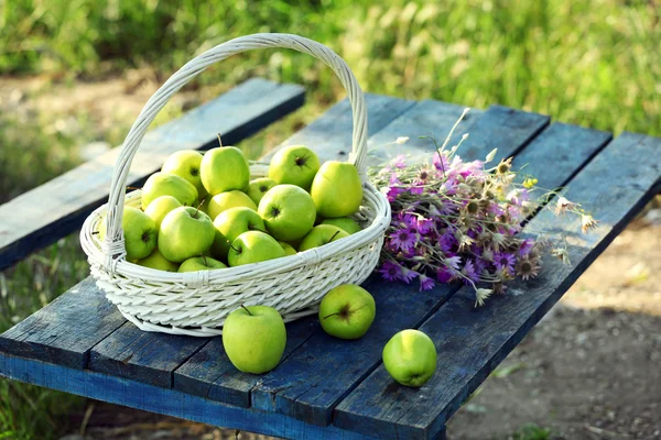 Green apples with bouquet of wildflowers — Stock Photo, Image