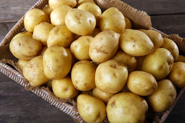 Nieuwe aardappelen in lade op houten tafel, close-up — Stockfoto