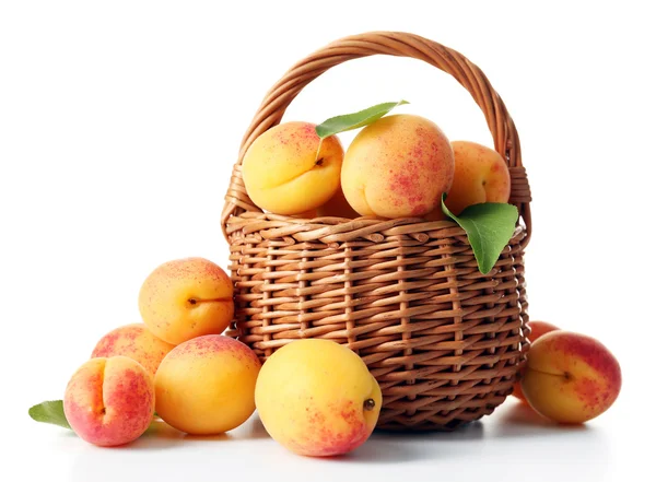 Rijp abrikozen in rieten mand geïsoleerd op wit — Stockfoto