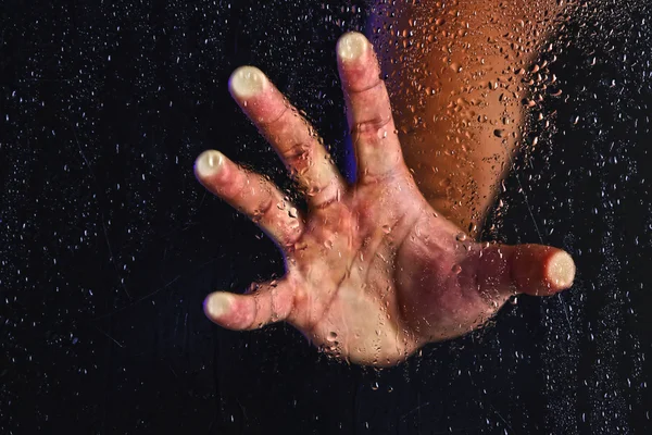 Manlig hand bakom våta glas — Stockfoto