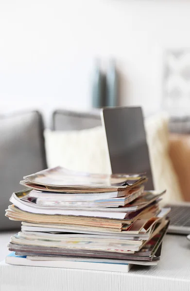 Magazines and laptop on table