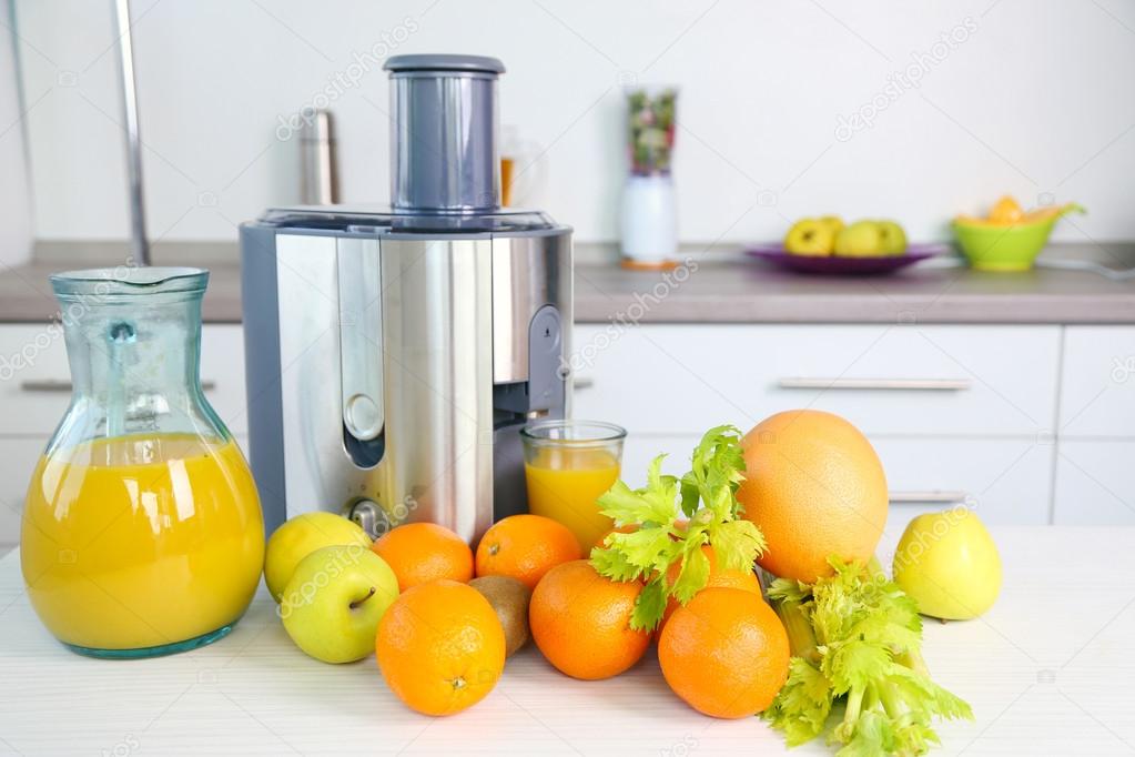 Juicer and fruits on table