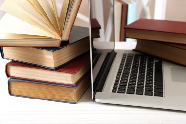 Masada dizüstü bilgisayar ile kitap yığını kapat