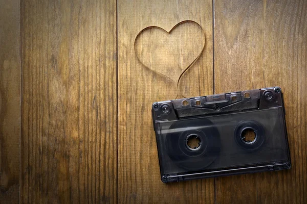 Cassette de audio con cinta magnética en forma de corazón sobre fondo de madera — Foto de Stock