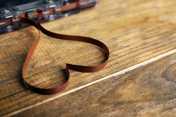 Audio cassette with magnetic tape in shape of heart on wooden background — Stock Photo, Image