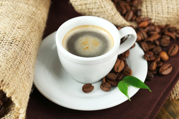 Xícara de café com grãos na mesa de perto — Fotografia de Stock