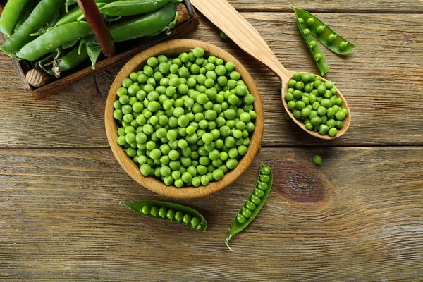 Fresh green peas in bowl and spoon on table close up — Stock Photo, Image